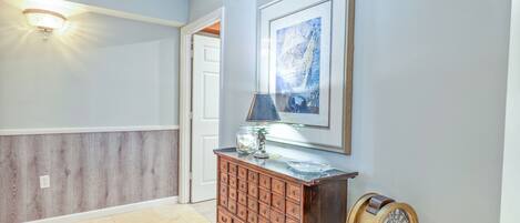 A hallway with a wooden cabinet, a framed artwork, and a vintage-style wall sconce.