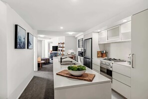 Een moderne keuken met witte kasten, een roestvrijstalen koelkast, een gasfornuis en een kom met limoenen op het eiland.