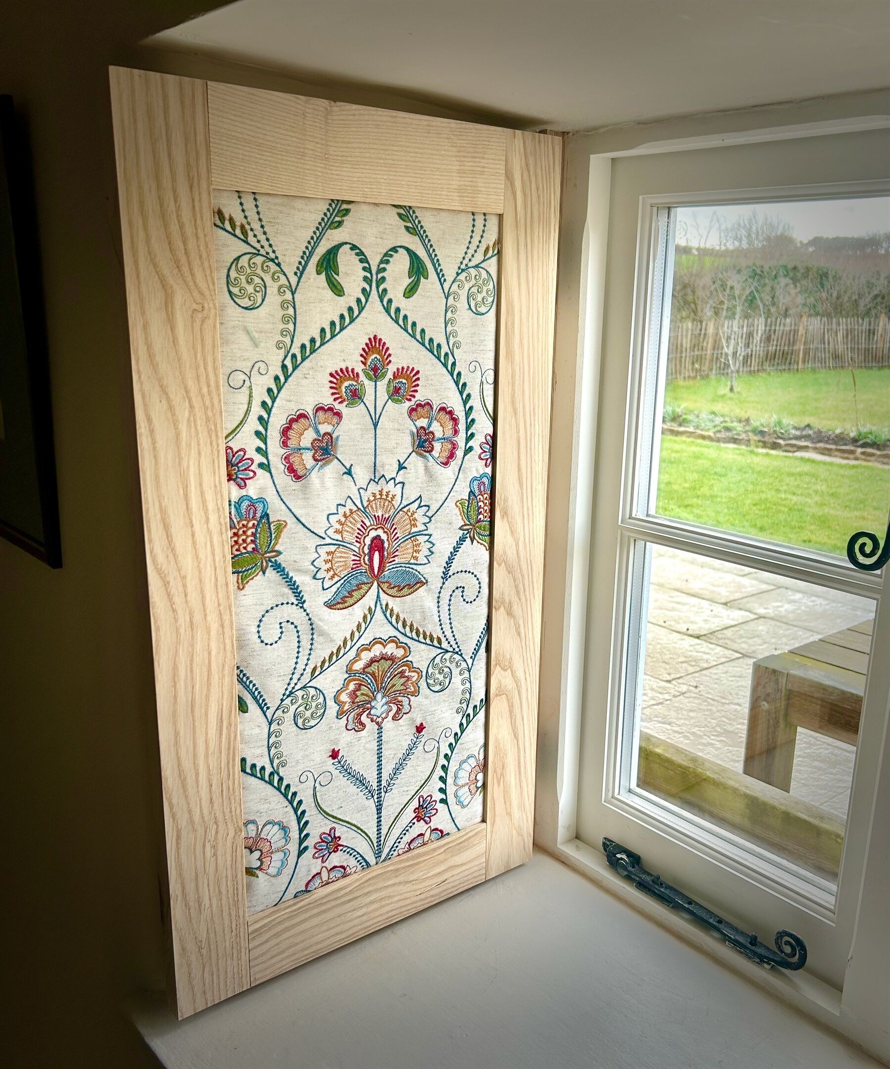 Una ventana con marco de madera y un estampado floral.