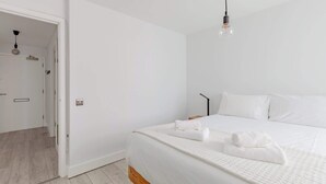 Ein modernes Schlafzimmer mit einem großen Bett, weißer Bettwäsche und einer Pendelleuchte.