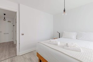 Ein modernes Schlafzimmer mit einem großen Bett, weißer Bettwäsche und einer Pendelleuchte.
