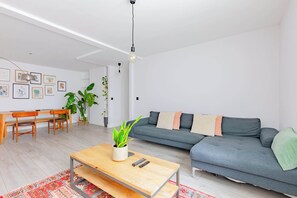 A modern living room with a grey sofa, wooden coffee table, and a dining area with a bench and chairs. - Spacious 2BD Flat By Docklands, Canary Wharf (Greater London)