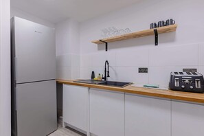Een moderne keuken met een roestvrijstalen koelkast, een houten aanrecht, een spoelbak met een kraan en een broodrooster.
