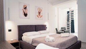 A modern hotel room with a large bed, a small bedside table, a chair, and a staircase in the background. - Acqua Marina (Balestrate)