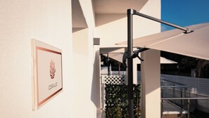 A sign with the name "CORALLO" on a white wall, a metal pole, and a white umbrella. - Acqua Marina (Balestrate)