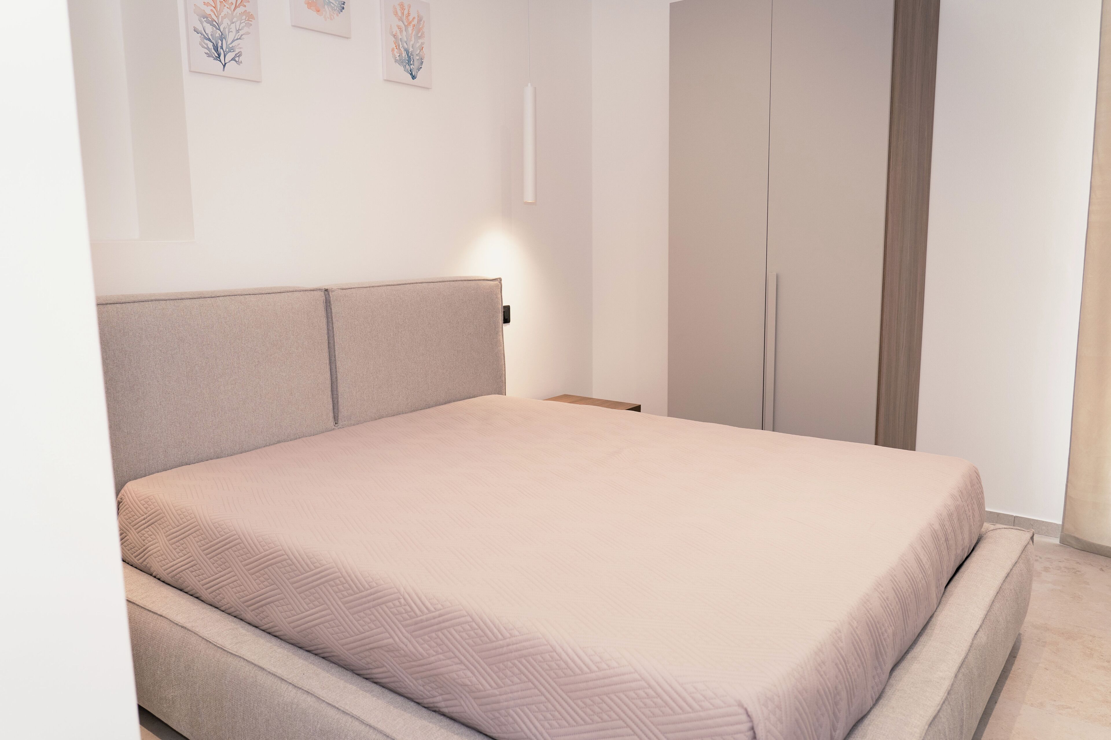 A bedroom with a bed, a wardrobe, and a nightstand.