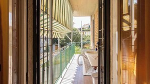 Un balcon donnant sur une marquise à rayures vertes et une balustrade blanche.