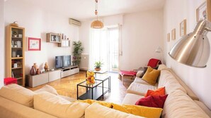 Un salon avec un canapé, une table basse, un téléviseur et une bibliothèque.