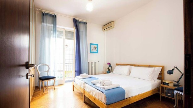 Une chambre à coucher avec un lit en bois, une chaise, un bureau et une fenêtre avec des rideaux.