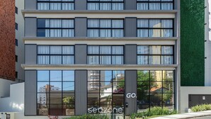 Un edificio de varios pisos con grandes ventanales y una pared verde.