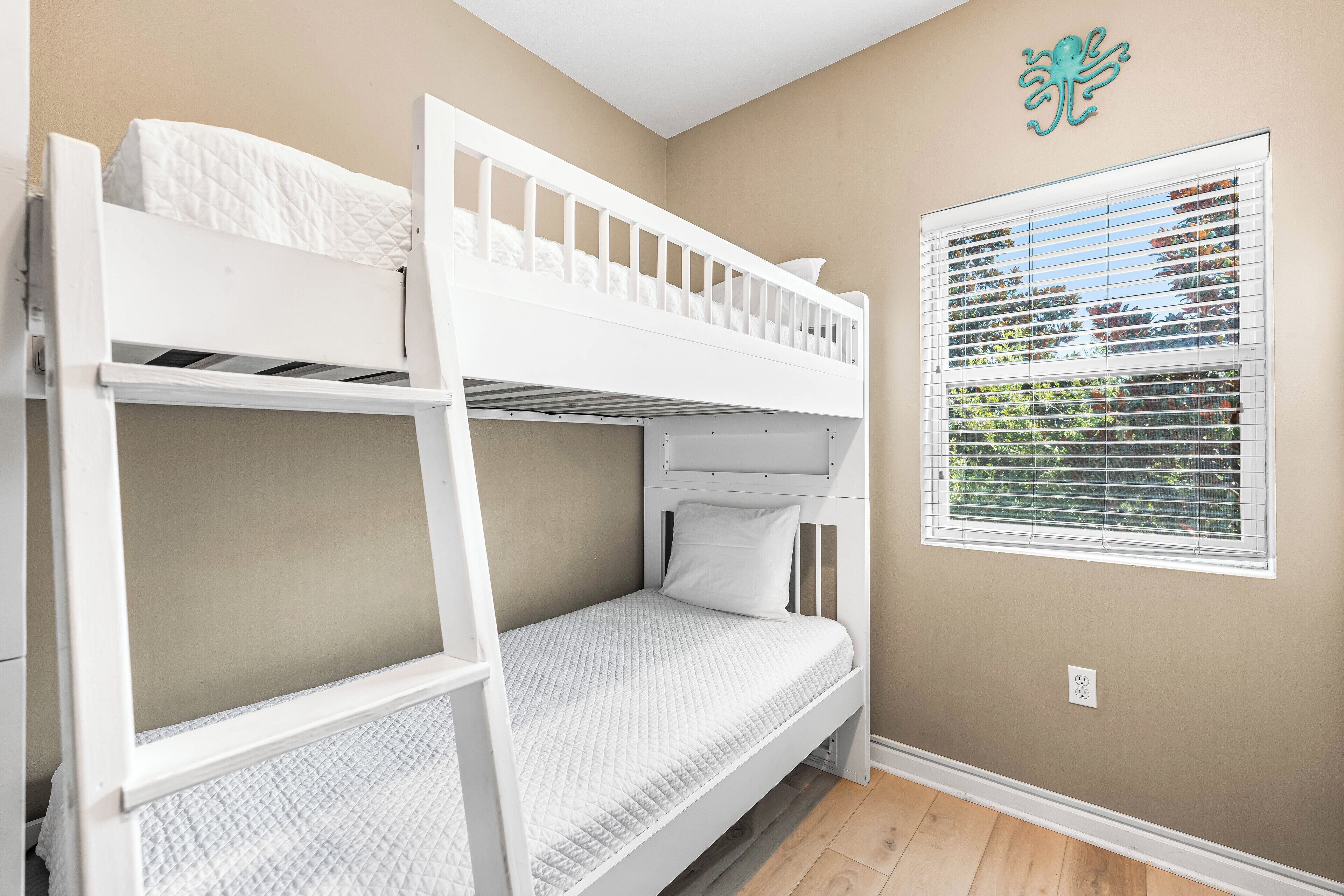 A bunk bed room with a window and a wall decoration.