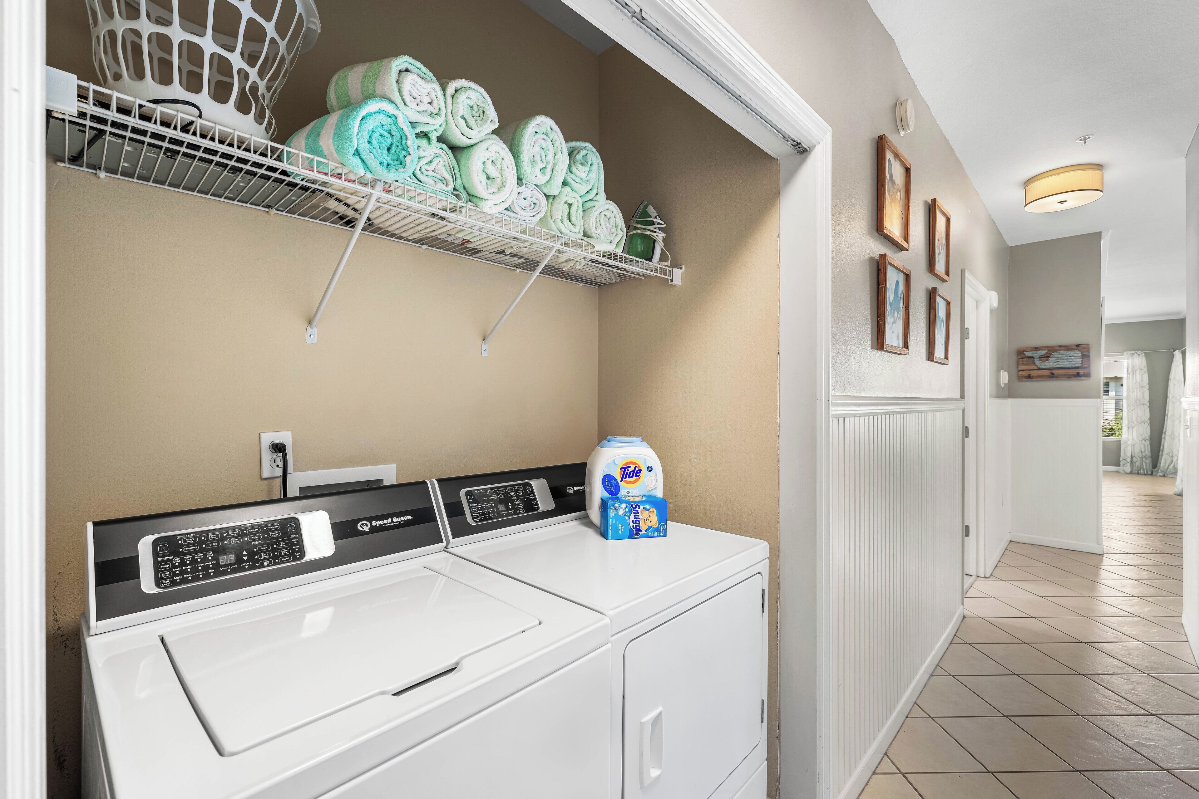 A laundry area with a washing machine, a drying rack with towels, and a detergent bottle.