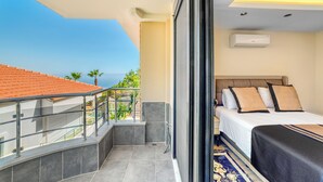 A hotel room with a balcony, a bed with white and brown bedding, and an air conditioning unit on the wall. - Modern 4-bedroom villa • Private pool - 10 min from Kleopatra beach (Antalya)