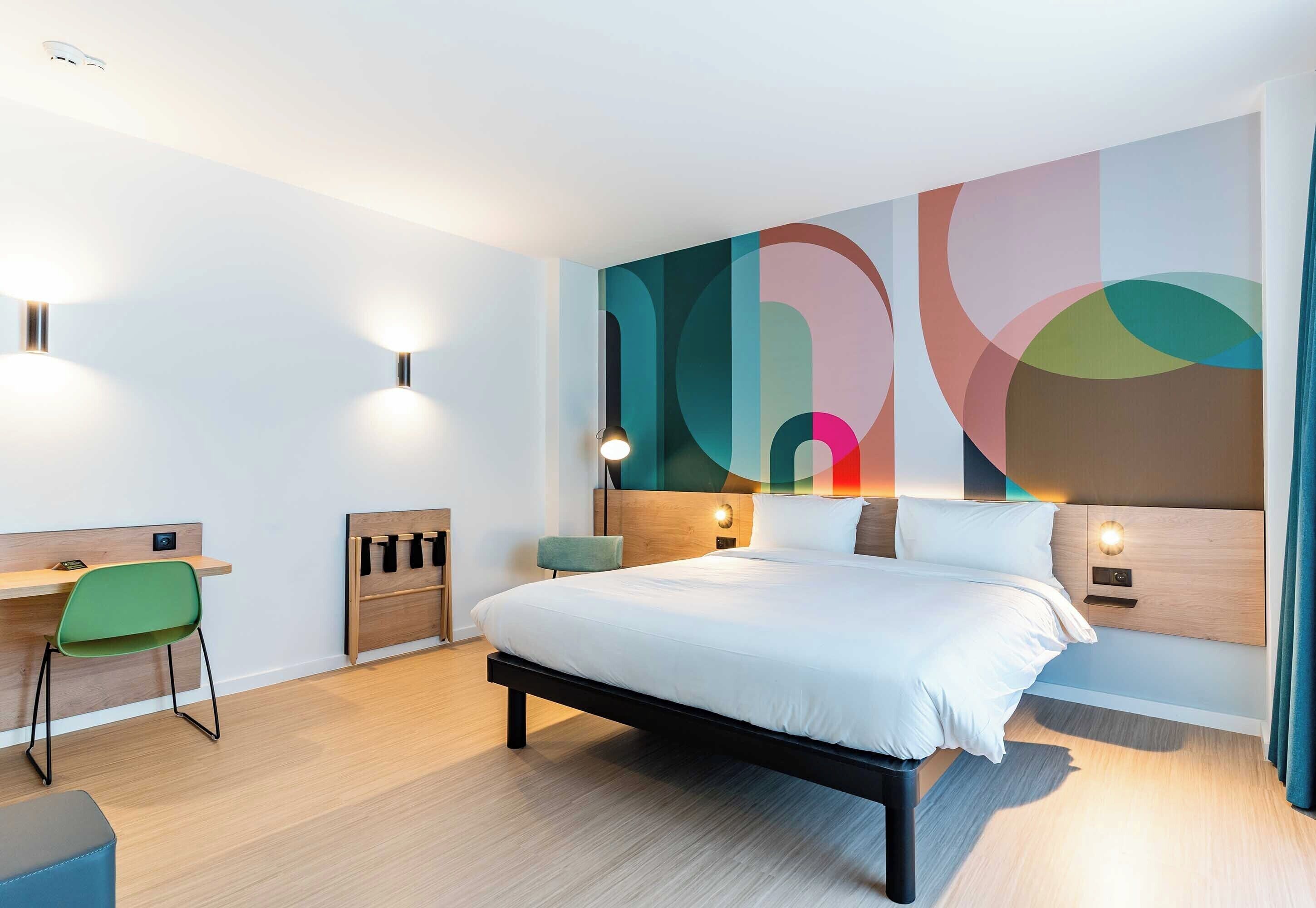 Una habitación de hotel moderna con una cama grande, un escritorio y una silla.