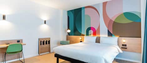 Una habitación de hotel moderna con una cama grande, un escritorio y una silla.
