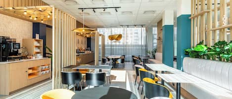 Un café moderno con una zona de estar central, una barra a la izquierda y otra zona de estar con sofás y mesas a la derecha.