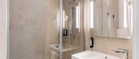 A modern bathroom with a glass-enclosed shower, a white sink, and a large mirror.