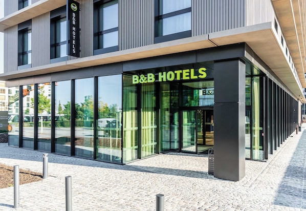 Un moderno hotel tipo B&B con amplios ventanales y entrada empedrada en piedra.