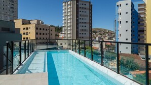 Ein Pool auf dem Dach mit einer Glasbrüstung, umgeben von Hochhäusern.