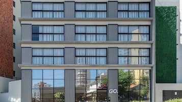 Un edificio de varios pisos con grandes ventanales y una pared verde.