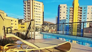 A rooftop pool area with lounge chairs and a view of surrounding buildings. - Studio w/ Swimming Pool in Pocos de Caldas Pgo0406 (Poços de Caldas)
