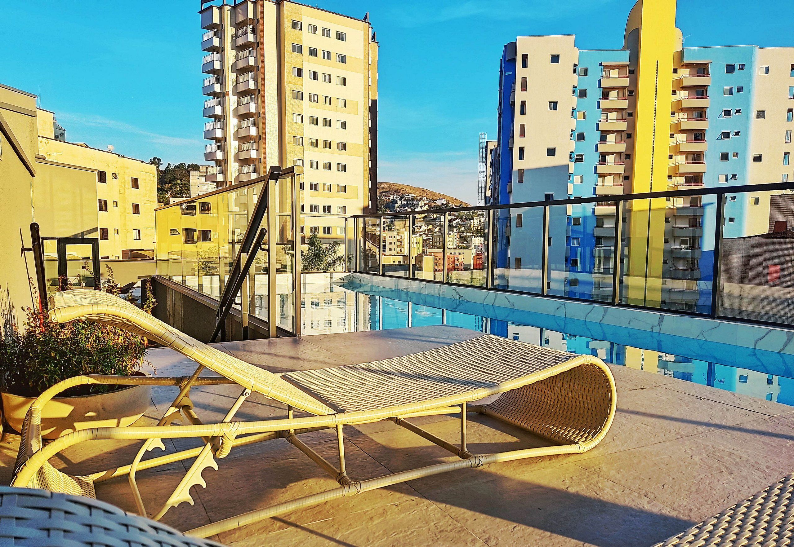 Zona de piscina en la azotea con sillones reclinables y vistas de edificios circundantes.