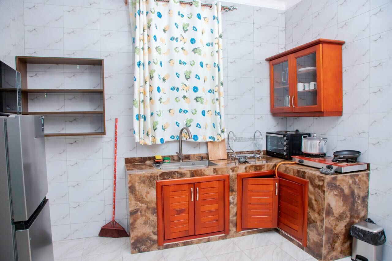 A compact kitchen with a refrigerator, microwave, stove, and wooden cabinets.