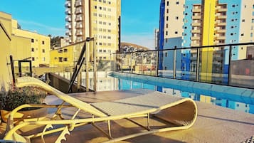 Tagterrasse med liggestole og udsigt til omkringliggende bygninger.