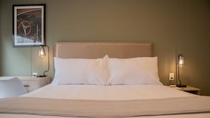 A neatly made bed with white linens, two bedside lamps, a framed picture on the wall, and a small bedside table with a lamp. - w Striking 1BR Duplex in Miraflores (Lima)