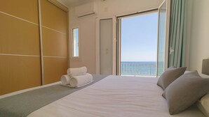A hotel room with a large bed, a view of the sea through a balcony, and a sliding door leading to another room. - Beachfront Ela Luxury Stay With Jacuzzi Views (Kithira)