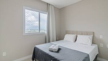 A bedroom with a bed, a window, and a view of the city.