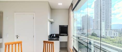 A modern apartment with a balcony, a dining area with a table and chairs, and a kitchen area.