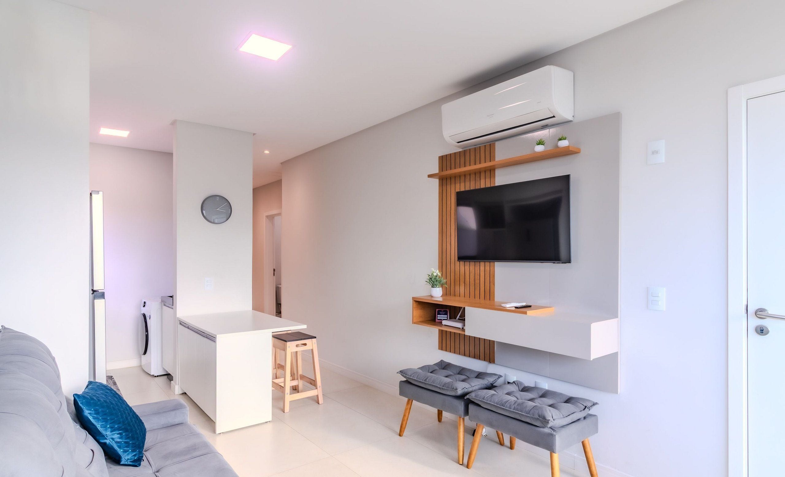 A modern living room with a grey sofa, a coffee table, and a TV mounted on the wall.