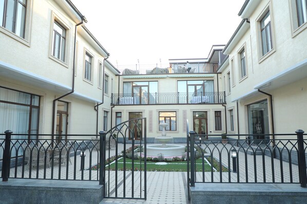 A courtyard with a central fountain, surrounded by buildings with balconies and large windows. - Mubina Hotel (Bukhara)