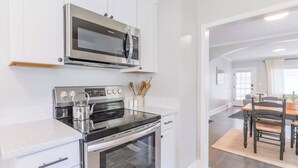 A modern kitchen with stainless steel appliances, white cabinetry, and a dining area with a wooden table and chairs.