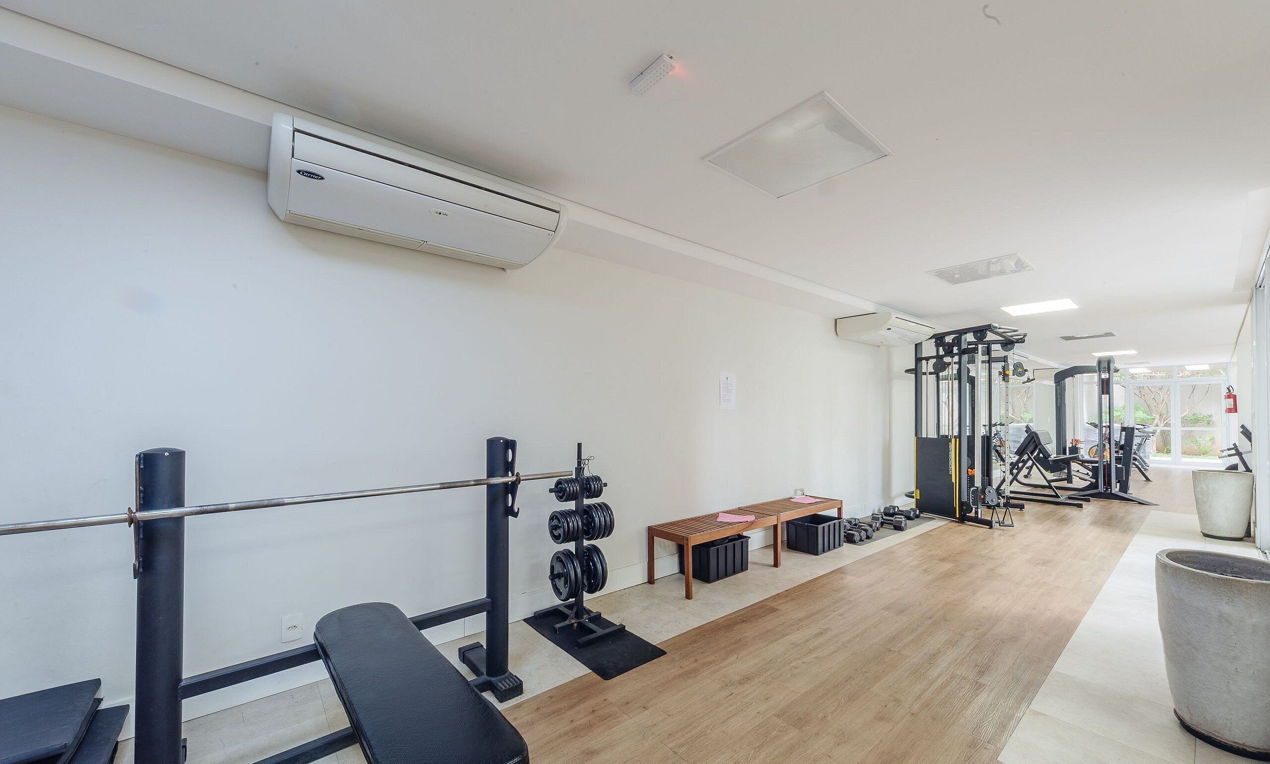 Un gimnasio con equipo de levantamiento de pesas, una banca y un espejo.