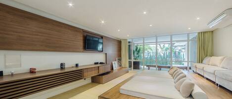 Un dormitorio moderno con una cama grande, un televisor montado en la pared y vistas al exterior.