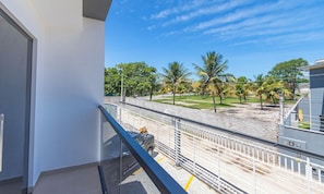 Un balcón con vista a una playa de arena y palmeras.