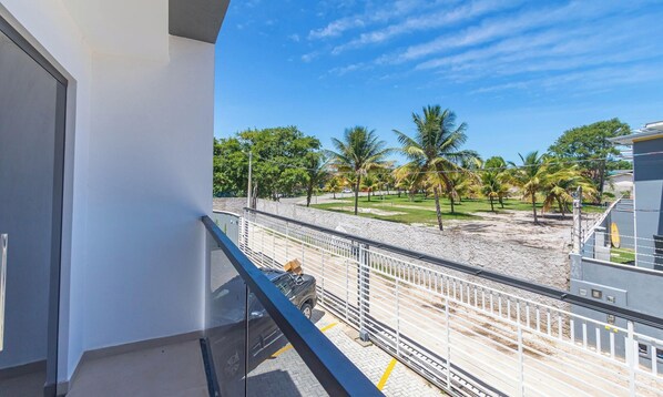 Un balcón con vista a una playa de arena y palmeras.