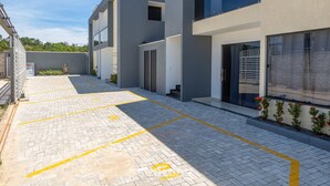 A modern building with a paved courtyard, marked parking spaces, and a small garden area. - 2-bedr Apt With Pool, 850m From the Beach Pdm005 (Porto Seguro)