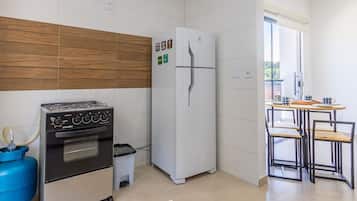 A compact kitchen with a gas stove, oven, white refrigerator, and a small dining area with a table and chairs.