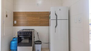 Una kitchenette compacta con estufa a gas, refrigerador y basurero.