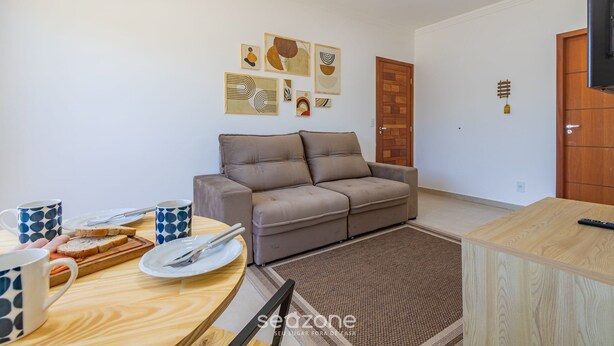 A living room with a sofa, a dining table with cutlery and plates, and artwork on the wall. - 2-bedr Apt With Pool, 850m From the Beach Pdm005 (Porto Seguro)