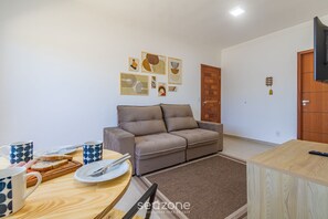 Un salon avec un canapé, une table à manger avec des couverts et des assiettes, et des œuvres d’art accrochées au mur.