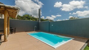 A rectangular swimming pool with a white edge, surrounded by a tiled patio. There is a wooden pergola structure to the left and a tall, cylindrical water tank in the background. - 2-bedr Apt With Pool, 850m From the Beach Pdm005 (Porto Seguro)