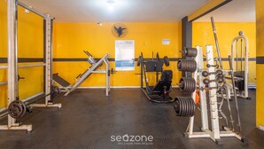 Un gimnasio con equipo de levantamiento de pesas, un ventilador y un letrero en la pared.