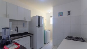 Una cocina con armarios blancos, un refrigerador, una estufa y una licuadora sobre la encimera.