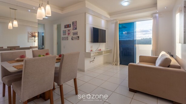 Una sala de estar moderna con comedor, un sofá y un televisor montado en la pared.