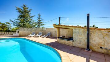 Una piscina con lettini, un muro in pietra e un pergolato.