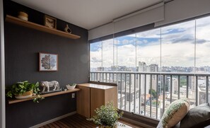 A modern balcony with a city view, wooden flooring, a small table, and a sofa with cushions.